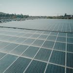 Sacramento solar inspection service: Rows of solar panels near a highway capture renewable energy under a clear sky.