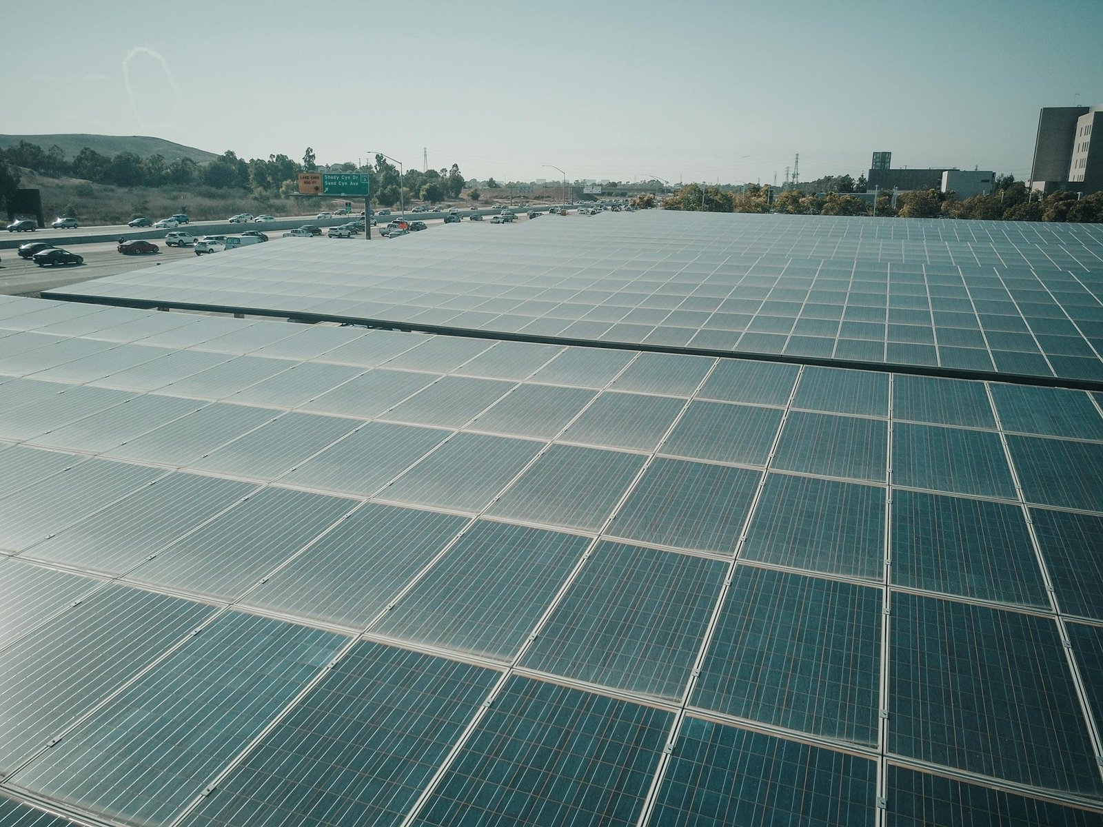 Sacramento solar inspection service: Rows of solar panels near a highway capture renewable energy under a clear sky.