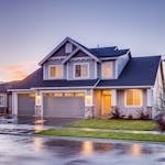 Buying a home with solar. Elegant suburban home with driveway at sunset showcasing modern architecture.