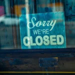 Intended to represent one of the many solar install companies that have gone out of business: retro "sorry we're closed" sign hanging in window
