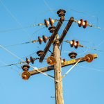 High voltage power line and insulators captured against a clear blue sky.