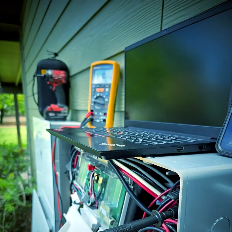 Laptop and multimeter being used to troubleshoot residential solar equipment
