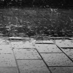 Monochrome image of raindrops creating splashes on a wet paved surface. How does winter affect solar system performance and will my electric bill go up?
